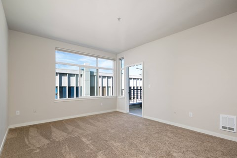 a living room with carpet and large windows and a door to a balcony